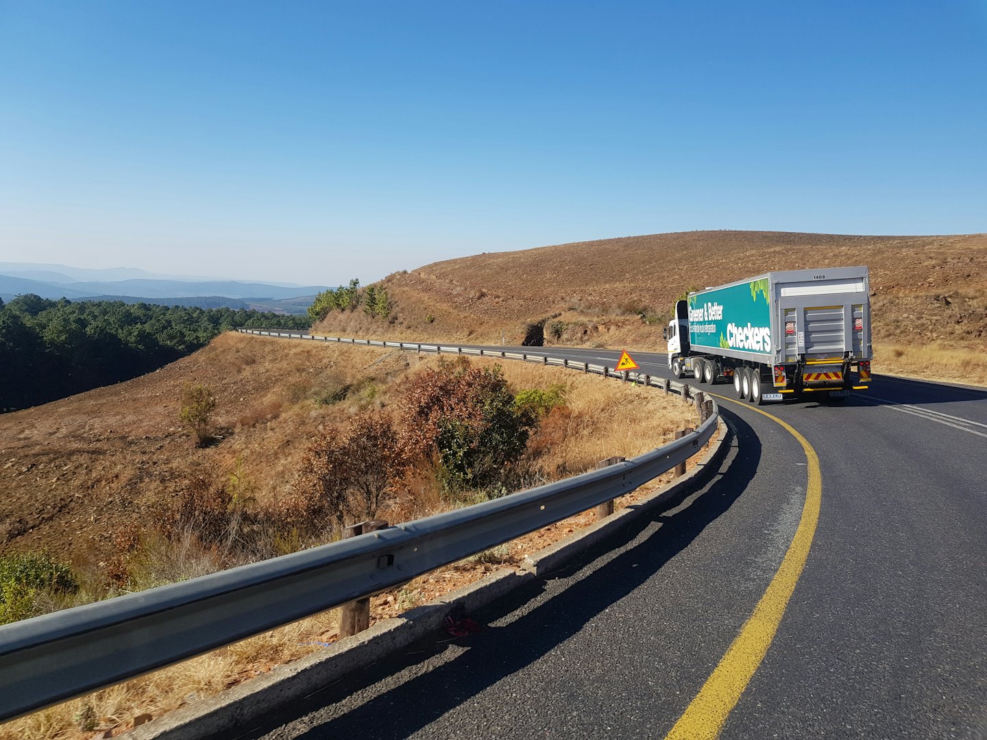 Un tráiler verde sube por una carretera sinuosa.