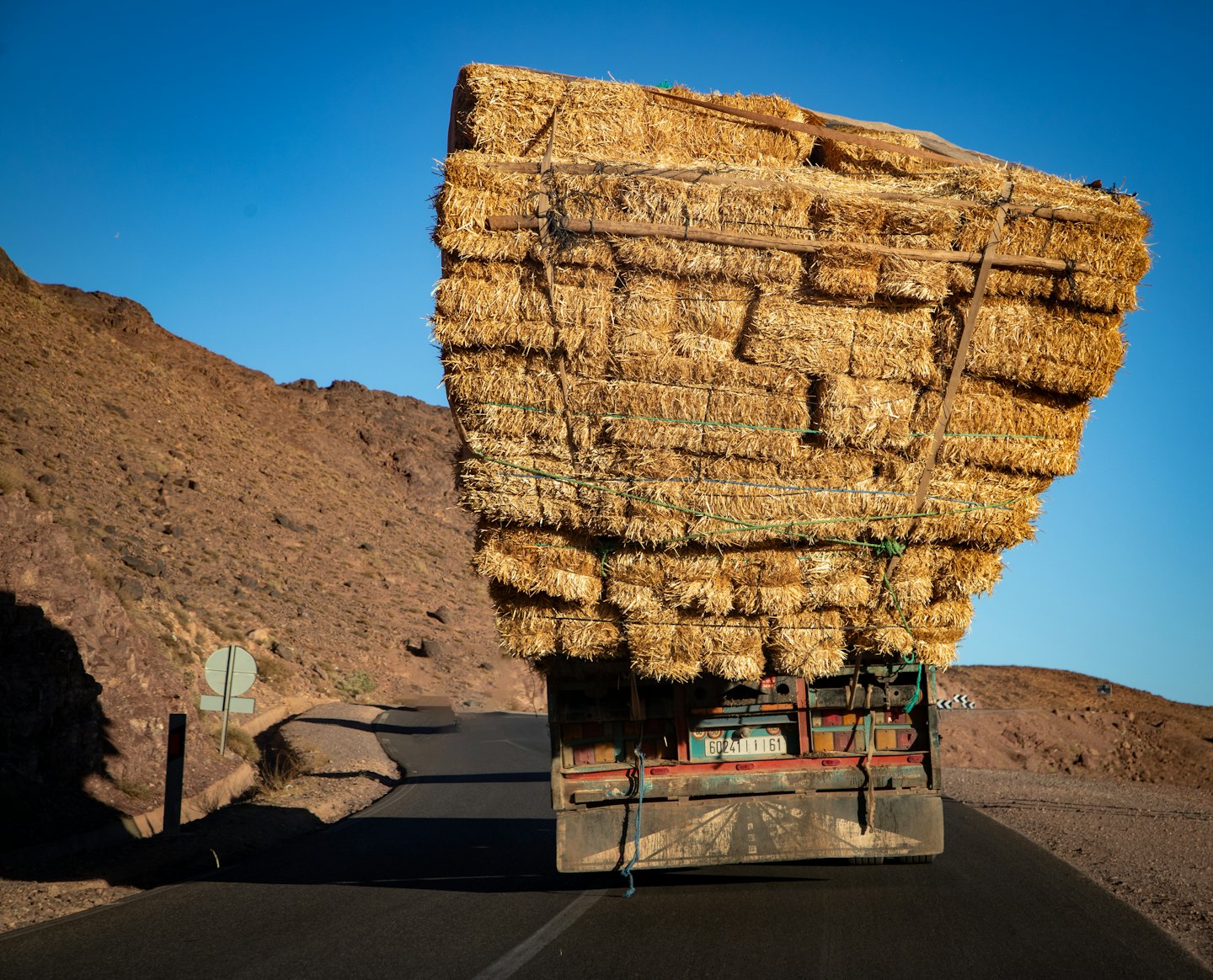 Un camión cargado de heno avanza por una carretera de montaña.